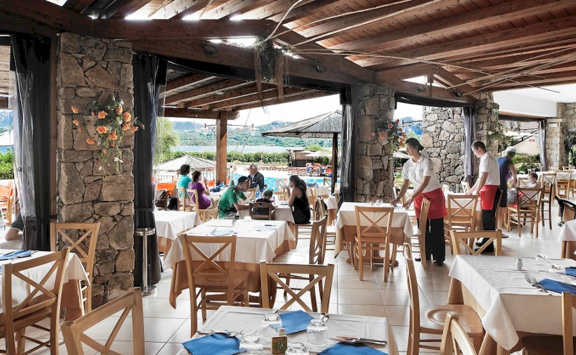 Innenansicht des Restaurants im Resort Cala Di Falco mit Gästen an Tischen und Blick auf den Pool.