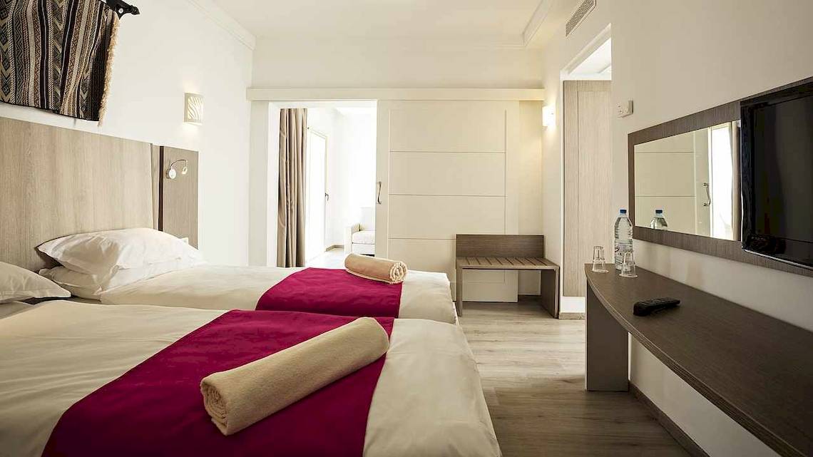 Zwei Doppelbetten mit roten Decken in einem Hotelzimmer im Robinson Djerba Bahiya.