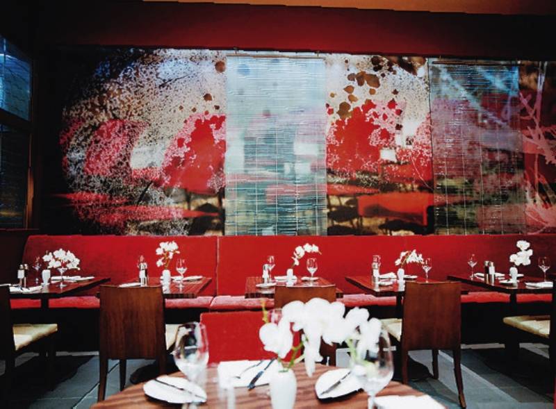 Das Hotel The Cumberland zeigt das Interieur seines Restaurants mit roten Sofas, gedeckten Tischen und einer großen Wandmalerei.
