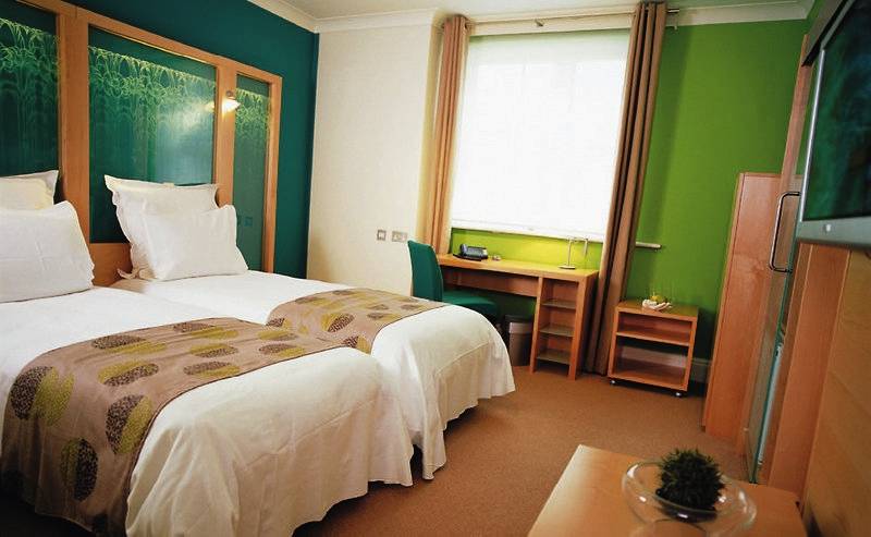 Doppelzimmer mit zwei Betten, grüne Wände, Schreibtisch und Fernseher.