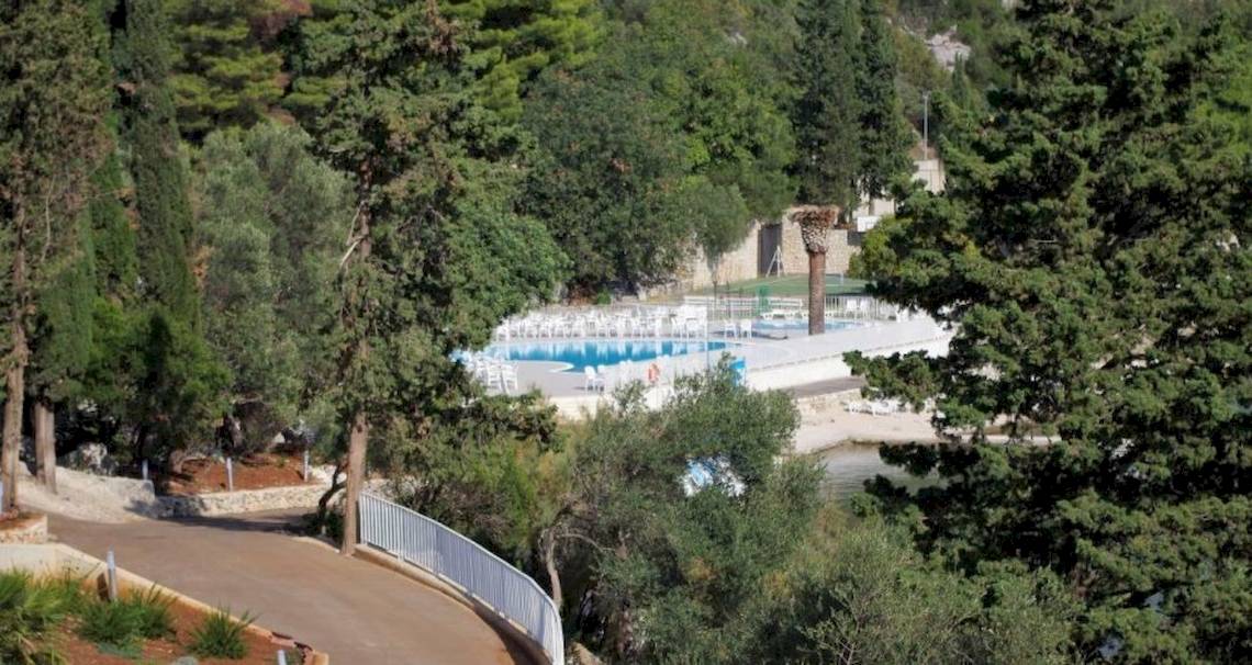 Außenpool des Osmine Slano Hotels umgeben von Bäumen und Wegen