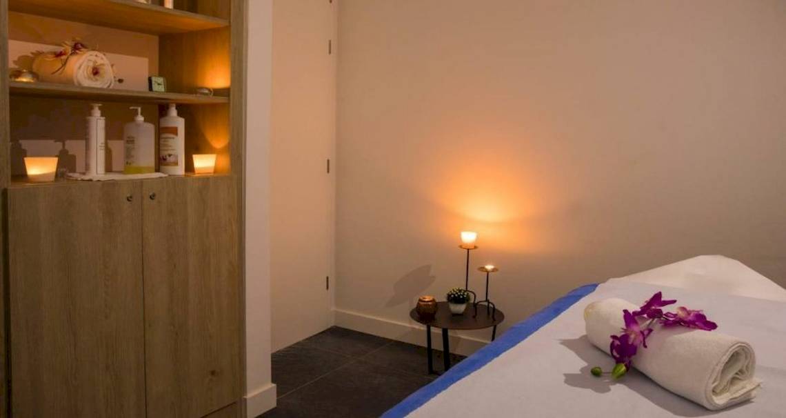 Spa-Behandlungsraum im Osmine Slano Hotel mit Massagetisch, Kerzen, Blumen und Pflegeprodukten.