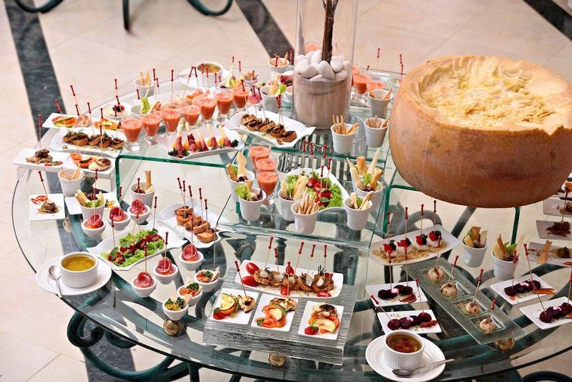 Buffet-Tisch mit verschiedenen Speisen im Hotel Bahia Principe Luxury Ambar, darunter Käsekuchen und Vorspeisen.