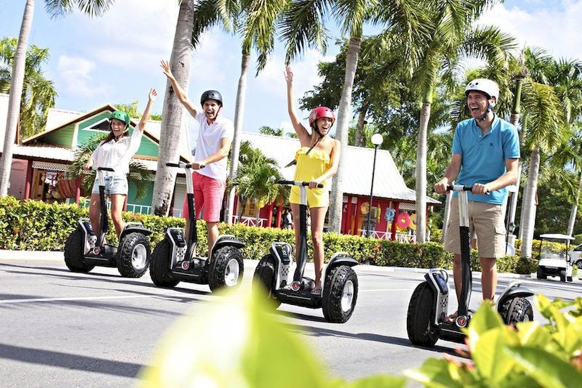 Vier Personen auf Segways fahren lächelnd im Freizeitpark.