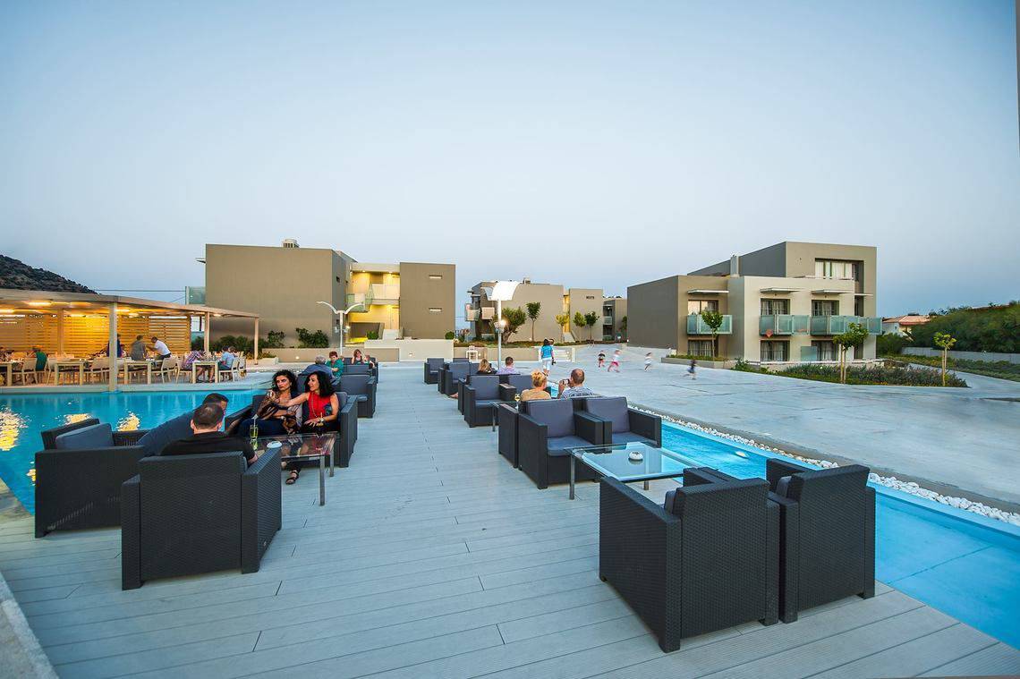 Außenbereich des Akti Palace Hotels mit Terrasse, Sitzmöbeln und Swimmingpool.