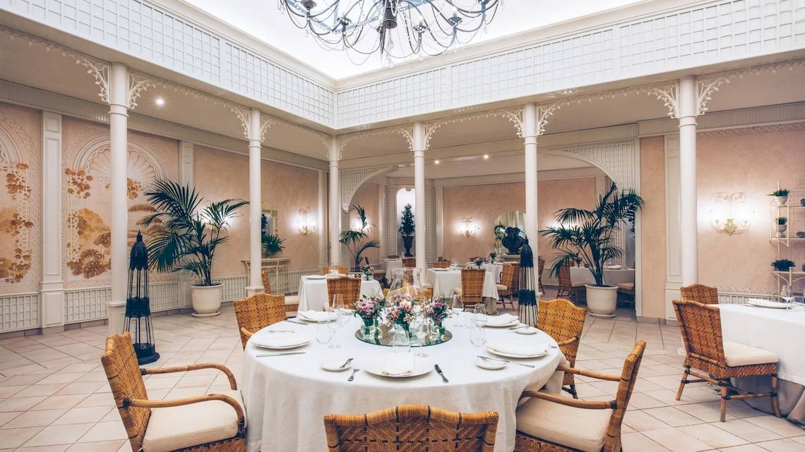 Elegantes Esszimmer im Iberostar Grand El Mirador mit Tisch, Stühlen und Pflanzen.