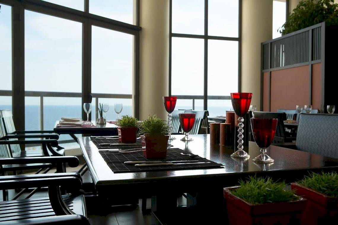 Restauranttisch im Ikos Oceania mit Meerblick und roten Gläsern.