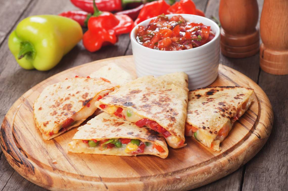 Gegrillte Quedillas mit Salsa und Paprika auf einem Holzteller.