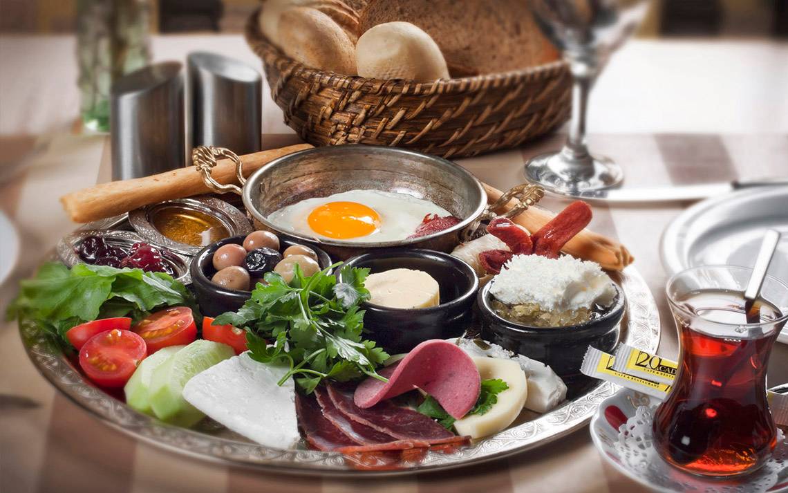 Frühstücksplatte mit Ei, Tee und verschiedenen Speisen auf einem Tisch serviert.