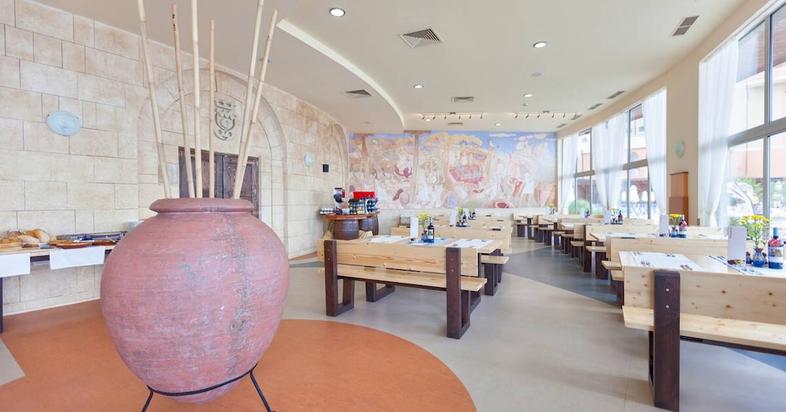 Restaurant im Sol Luna Bay All Inclusive Hotel mit gemauerten Wänden, großen Vasen und Holztischen.