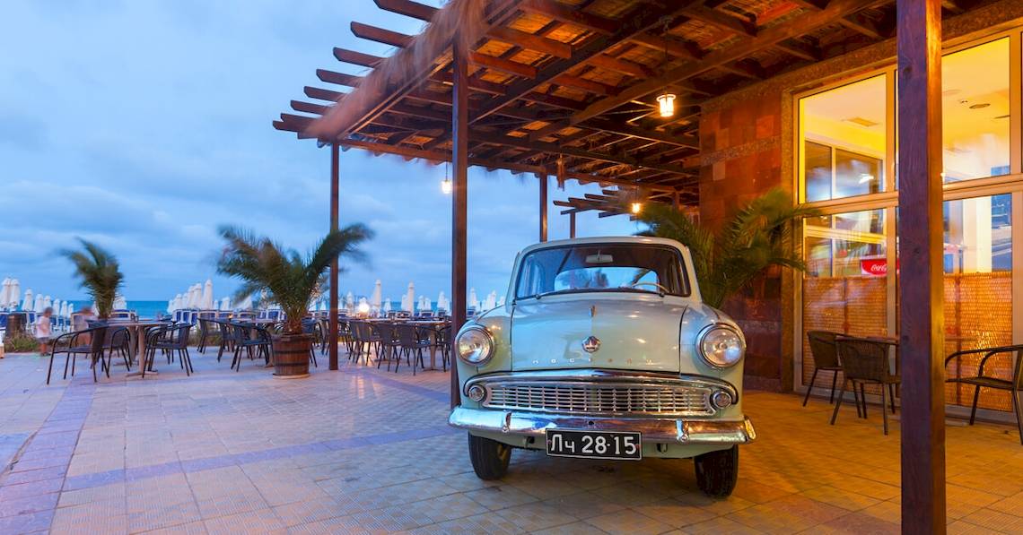 Ein altes Auto steht vor dem Sol Luna Bay All Inclusive Hotel am Abend.