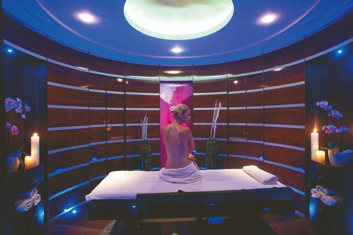 Spa-Behandlungsraum im Rhodes Bay Hotel & Spa mit einer Frau auf einer Liege und blauen Lichtern.