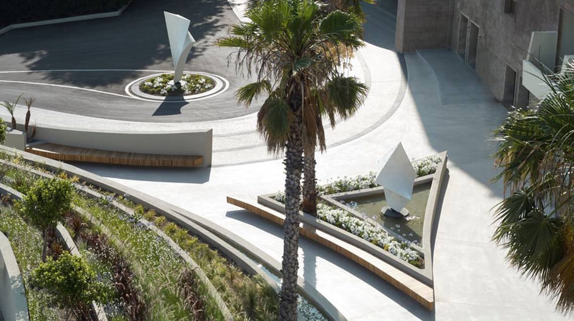 Aussenbereich des Rhodes Bay Hotel & Spa mit Palme, Brunnen und Garten