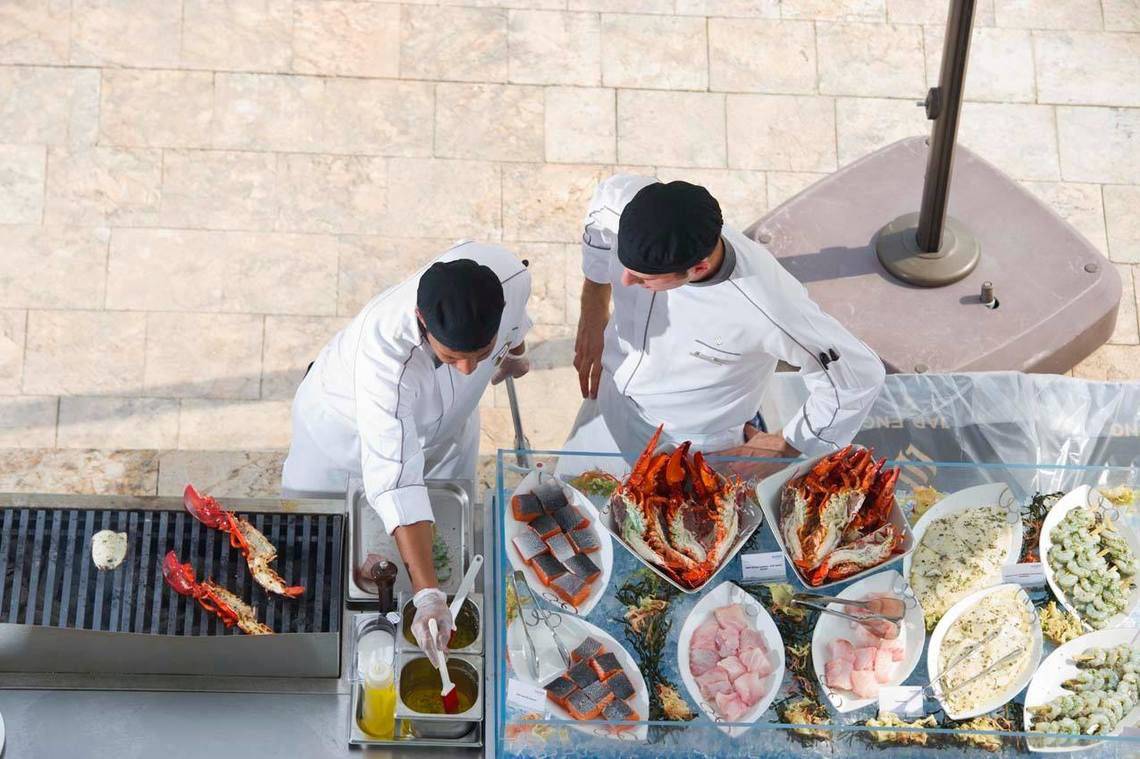 Küchenpersonal des Conrad Abu Dhabi Etihad Towers bei der Arbeit an einem Grill und einem Buffet.