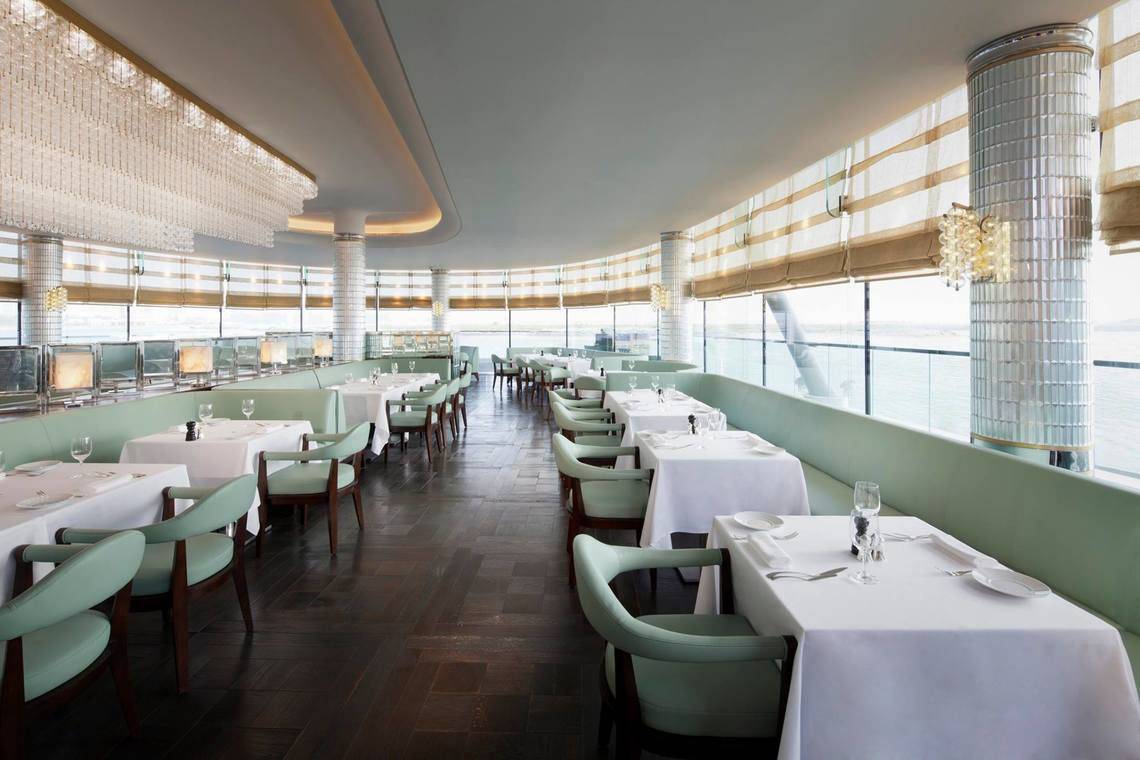 Innenansicht des Restaurants im Conrad Abu Dhabi Etihad Towers Hotel mit grünen Sitzen und Tischen.