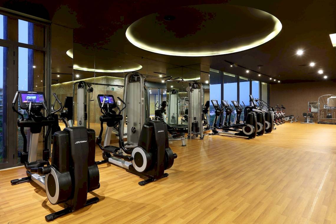 Fitnessstudio im TRS Coral Hotel mit vielen Geräten und einer großen Fensterfront.