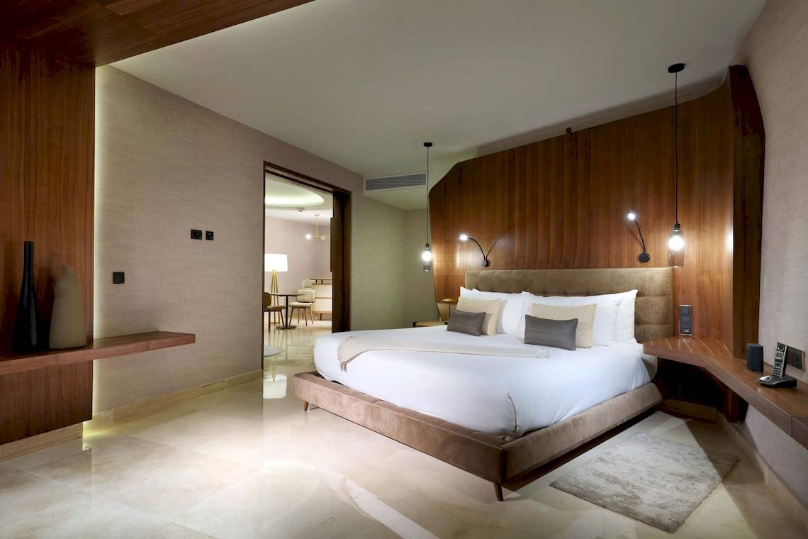 Schlafzimmer im TRS Coral Hotel mit einem großen Bett, Holzwänden und Beleuchtung.