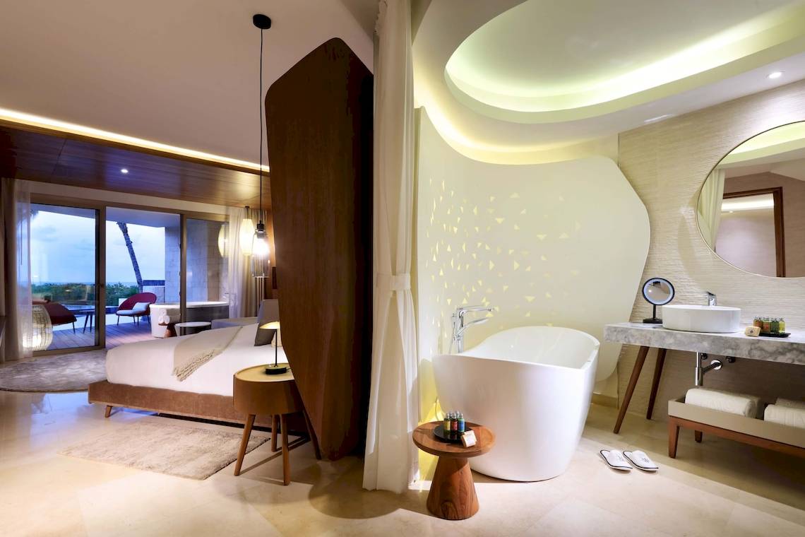 Innendesign eines Zimmers im TRS Coral Hotel mit Badewanne, Bett und Badezimmerspiegel.