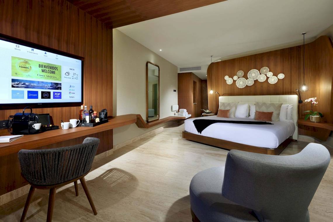 Innenansicht eines Zimmers im TRS Coral Hotel mit Bett, Fernseher und Schreibtisch