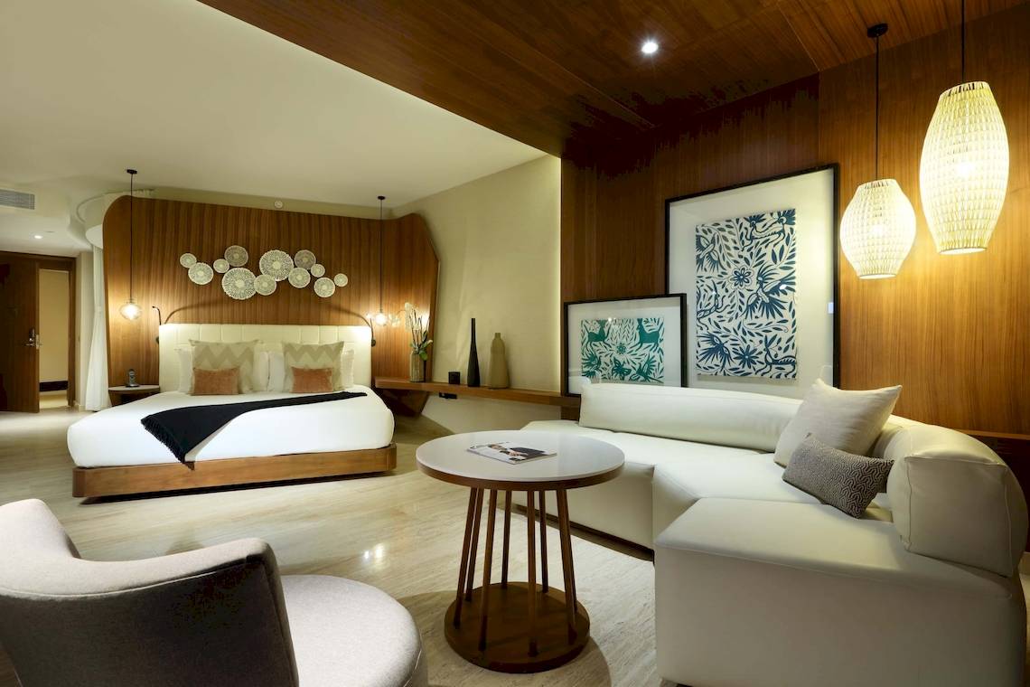 Innenansicht der Suite im TRS Coral Hotel mit Bett, Couch, Tisch und Dekor.