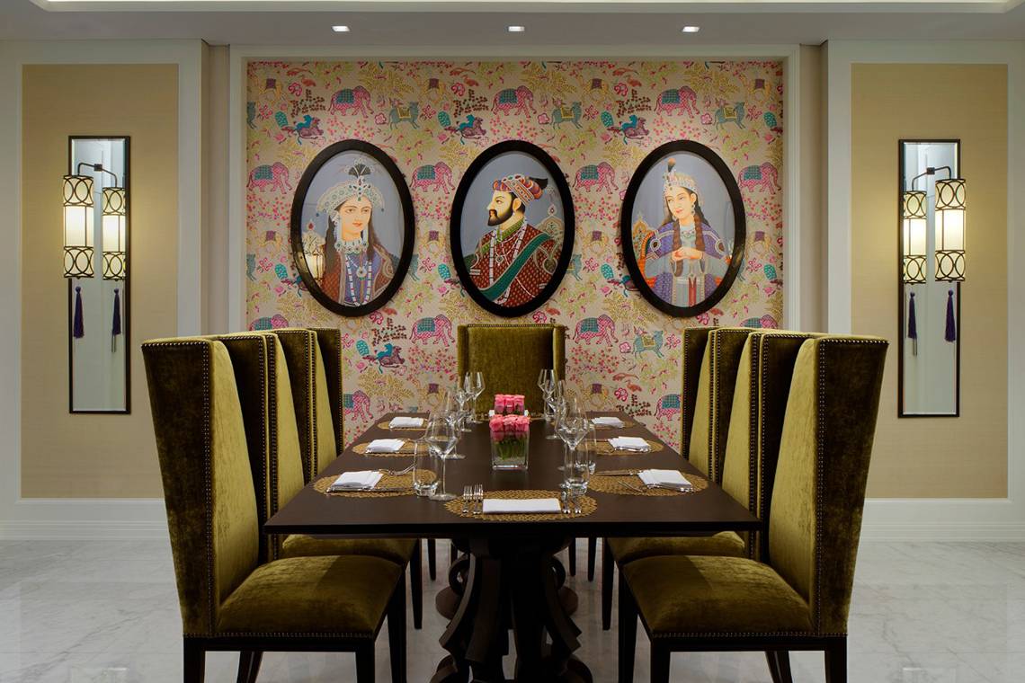 Speisesaal im Taj Dubai mit viktorianischen Porträts an der Wand und einem runden Tisch.
