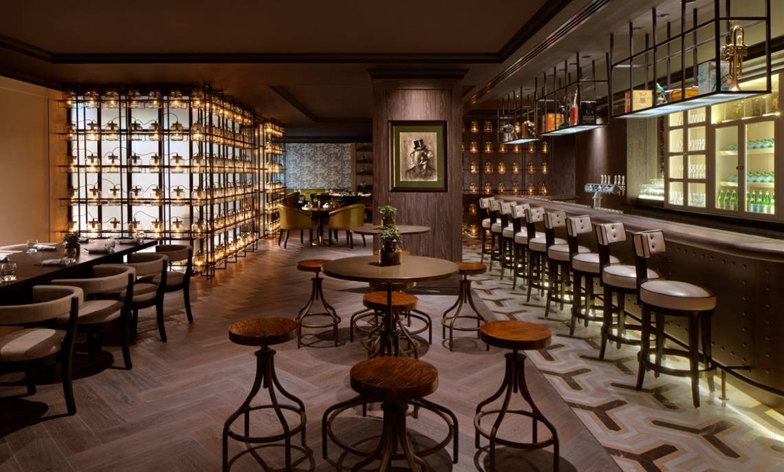 Innenansicht des Restaurants im Taj Dubai mit Holztischen, Stühlen und einem Porträt an der Wand.