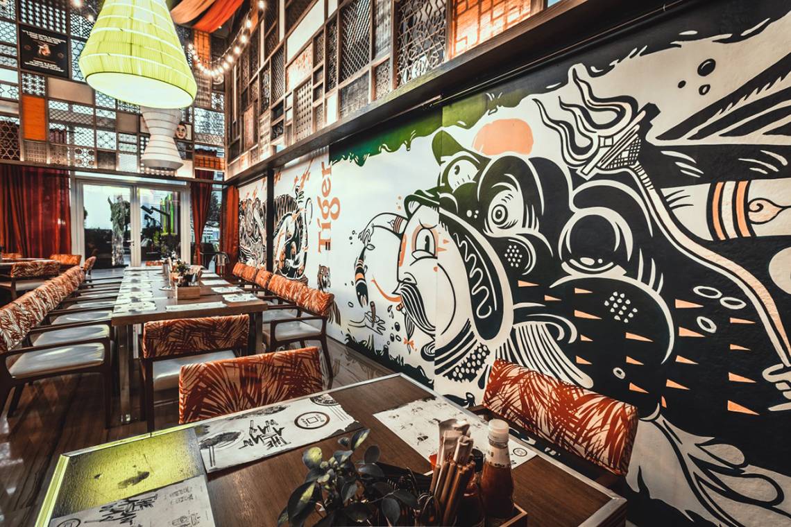 Innenbereich des Taj Dubai Restaurants mit einem großen Wandbild, das Tiger zeigt.