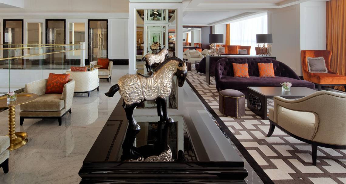 Lobby des Taj Dubai Hotels mit Möbeln, Lampen und einem Pferdekopf-Kunstwerk.