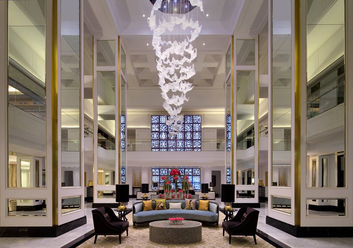 Foyer des Taj Dubai Hotels mit Kristallleuchte und Blumenarrangement.