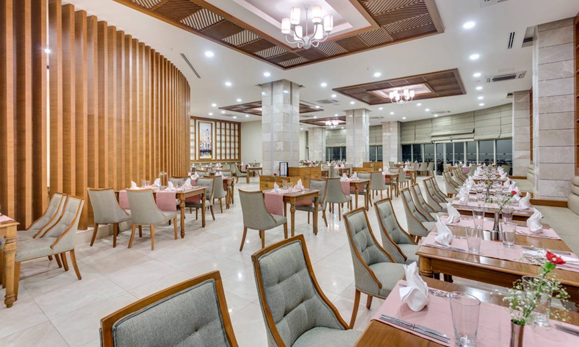Innenansicht des Restaurants im Sherwood Exclusive Lara Hotel mit gedeckten Tischen und Stühlen.
