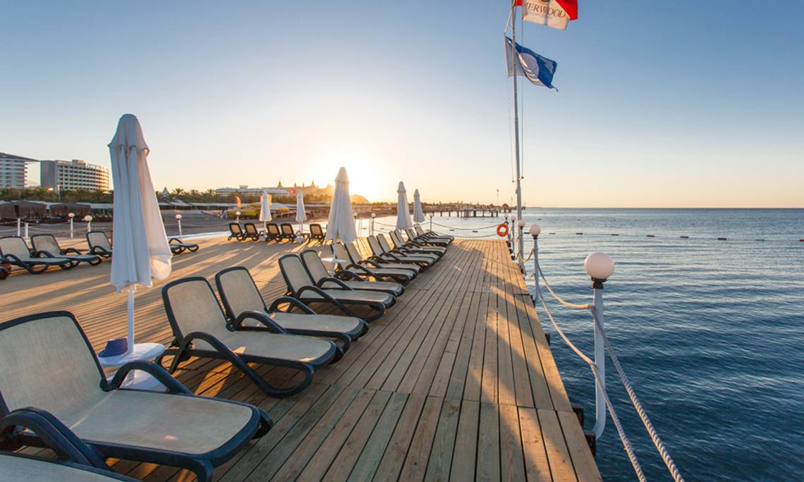 Hotelterrasse des Sherwood Exclusive Lara mit Sonnenliegen und Schirmen am Meer