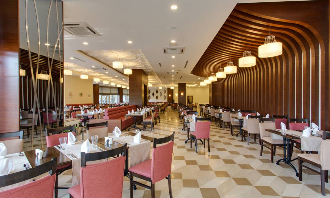 Innenansicht des Restaurants im Sherwood Exclusive Lara Hotel mit gemustertem Boden und elegant eingerichteten Tischen.