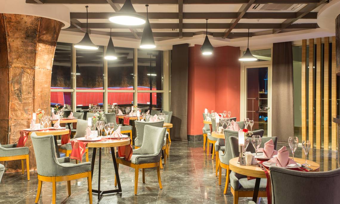 Innenansicht des Restaurants im Sherwood Exclusive Lara Hotel mit gedeckten Tischen und stilvollen Beleuchtung.