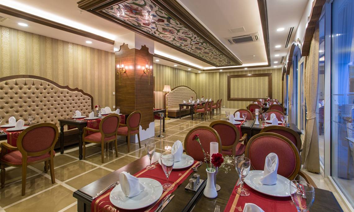 Restaurantbereich des Sherwood Exclusive Lara Hotels mit gedeckten Tischen und Stühlen.