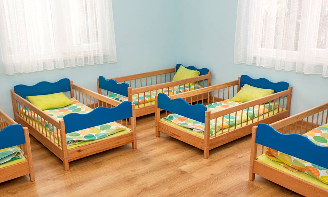 Ein Zimmer mit mehreren blauen Kinderbetten auf hölzerne Böden, jeden mit gelben Kissen