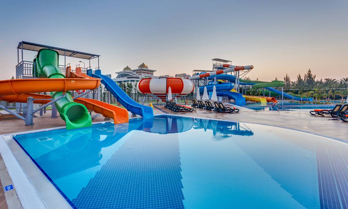 Wasserpark des Sherwood Exclusive Lara Hotels mit mehreren Wasserrutschen und Sonnenliegen.