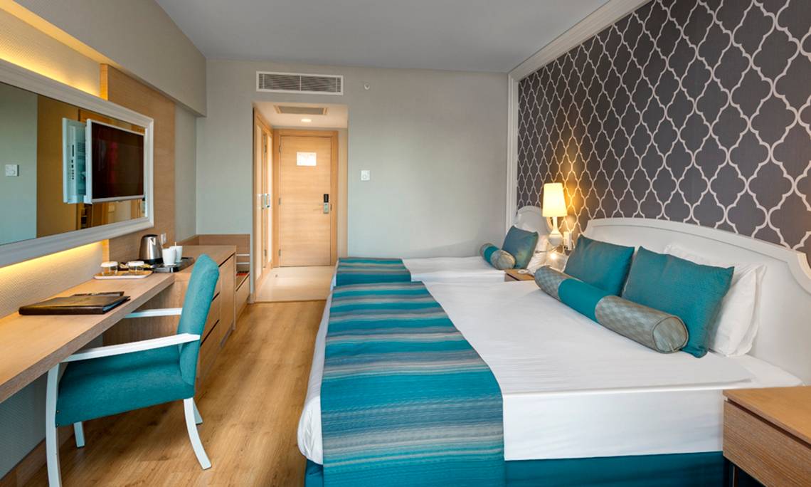 Doppelzimmer im Sherwood Exclusive Lara Hotel mit zwei Betten, Schreibtisch und Fernseher.
