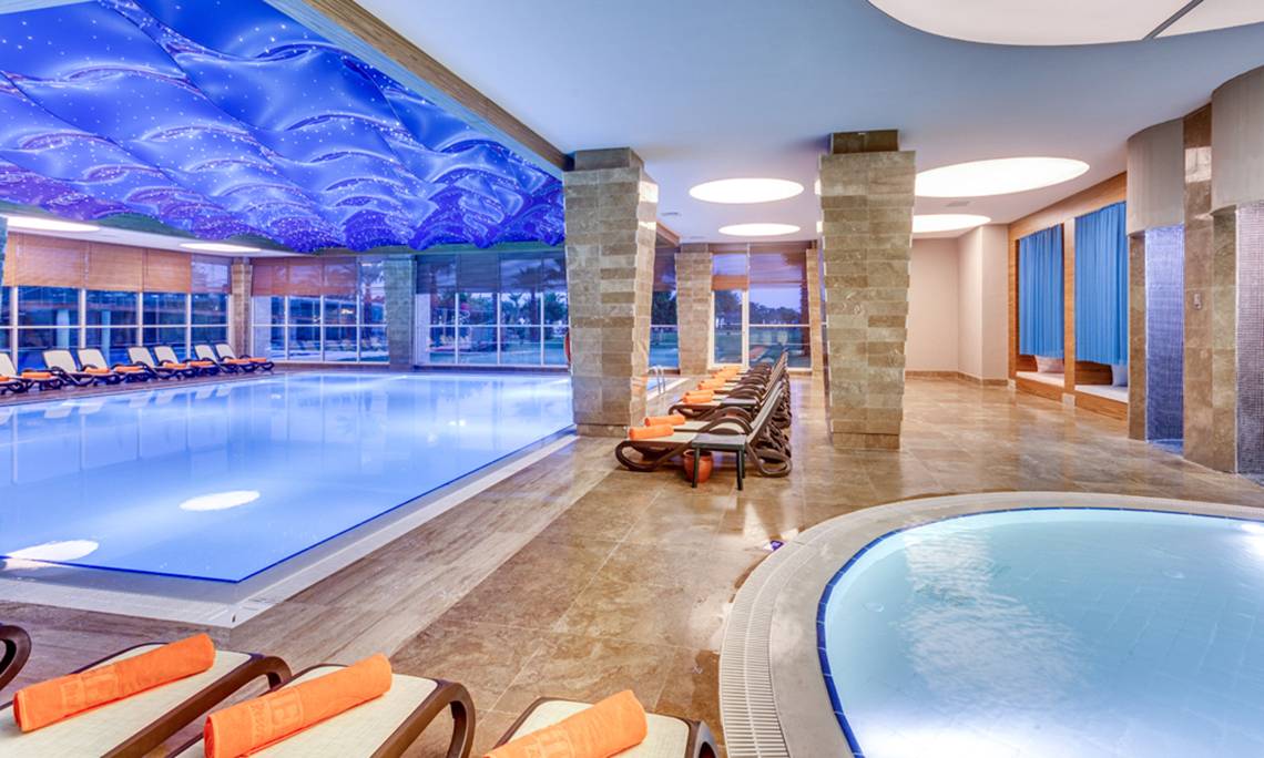 Innenbereich des Sherwood Exclusive Lara Pools mit blauer Decke und Loungestühlen