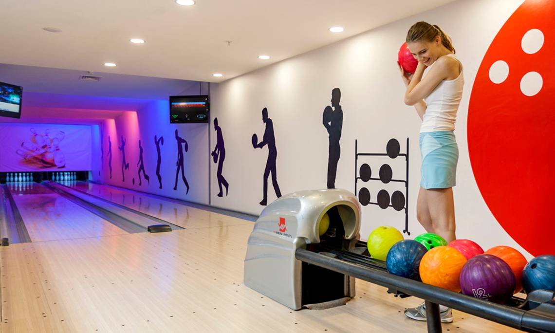 Frau im Sherwood Exclusive Lara Hotel in der Bowlinghalle, die eine Bowlingkugel hält.