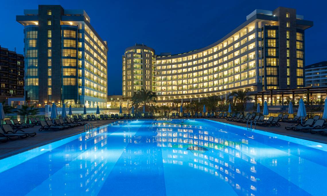 Sherwood Exclusive Lara Hotel Pool bei Nacht mit beleuchteten Gebäuden und Sonnenliegen