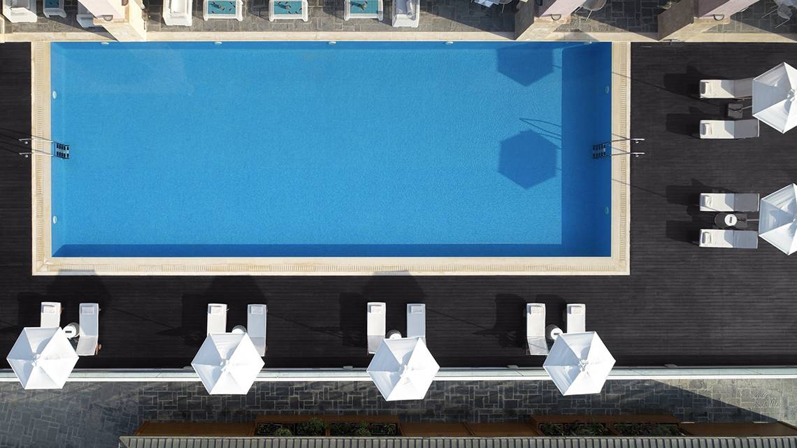 Obersicht des Pools im Boutique 5 Hotel & Spa mit weißen Sonnenschirmen und Liegestühlen.