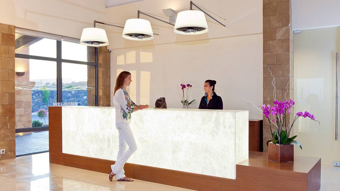 Empfangsbereich im Boutique 5 Hotel & Spa mit einer Rezeptionistin und einer Frau, die an der Rezeption steht.