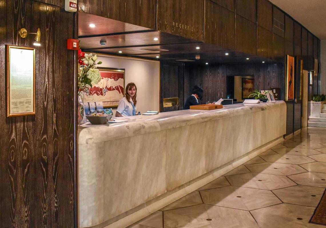 Empfangsbereich des Creta Star Hotels mit einer Rezeptionistin, die einen Gast bedient.
