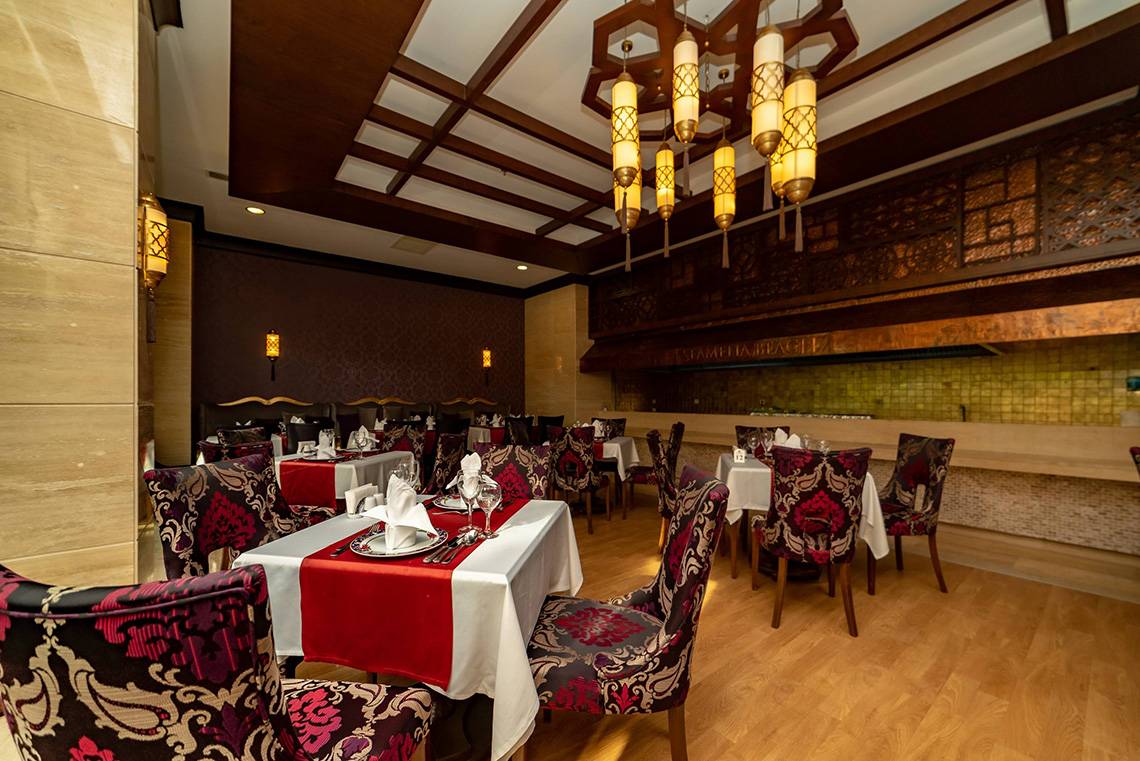 Innenansicht des Restaurants im Seamelia Beach Resort & Spa mit gedeckten Tischen und hängenden Laternen.