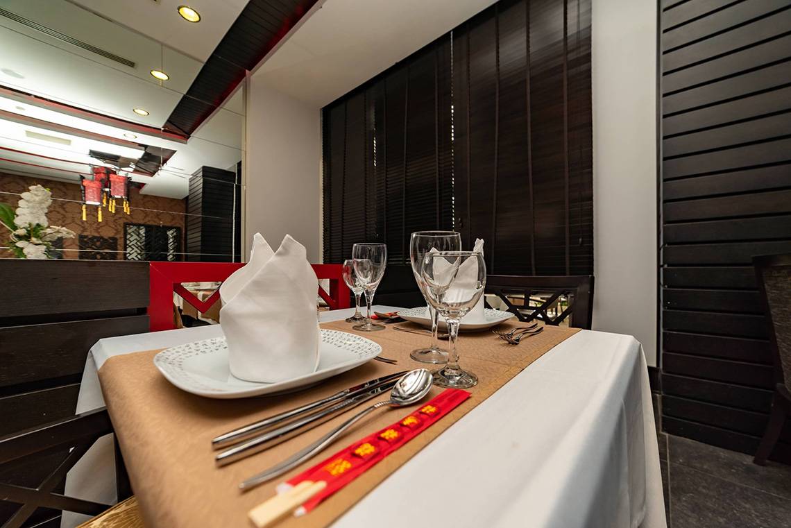 Tisch im Hotelrestaurant des Seamelia Beach Resort & Spa mit Platzkarten, Besteck und Gläsern.