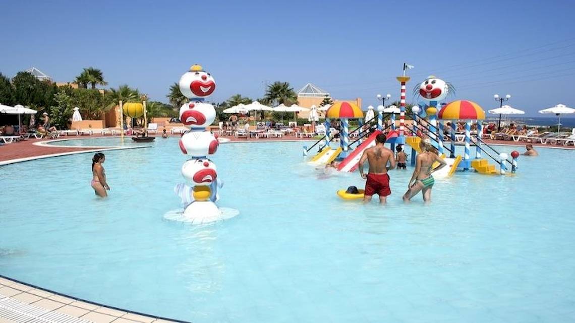 Menschen spielen im Poolbereich des Royal & Imperial Belvedere Hotels, umgeben von bunten Wasserspielgeräten.