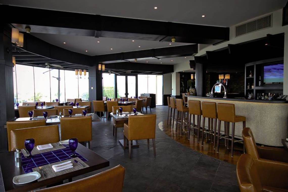 Innenansicht des JA Palm Tree Court Restaurants mit Bar, Tischen und Stühlen.