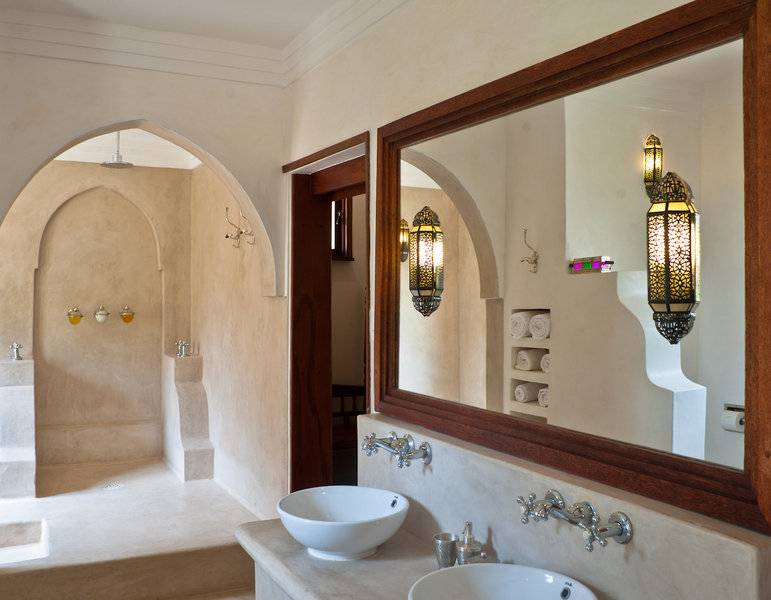 Badezimmer im Swahili Beach Resort mit zwei Waschbecken, einem Spiegel und einer Dusche.