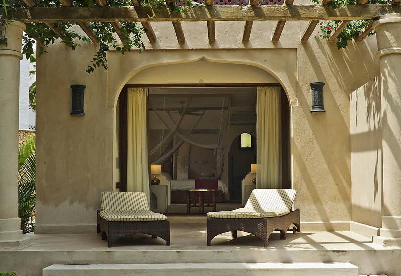 Terrasse des Swahili Beach Resorts mit zwei Liegen und Blick auf das Zimmer.