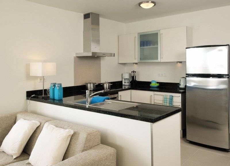 Inneneinrichtung der Küche im Blue Bay Curacao Golf & Beach Resort mit weißem Kühlschrank und schwarzem Granit-Arbeitsplatte.